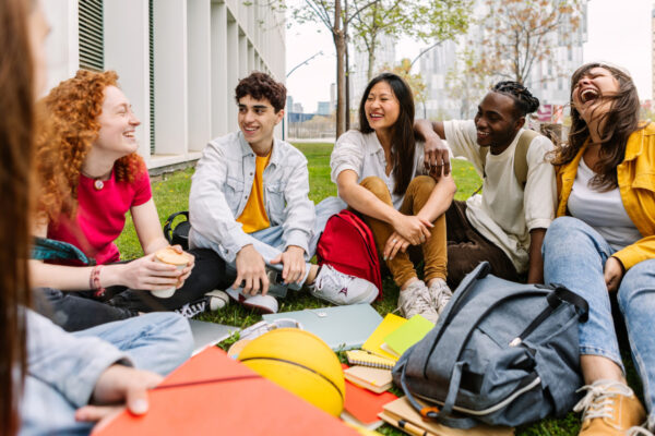 group of college students sat in the grass at the campus
